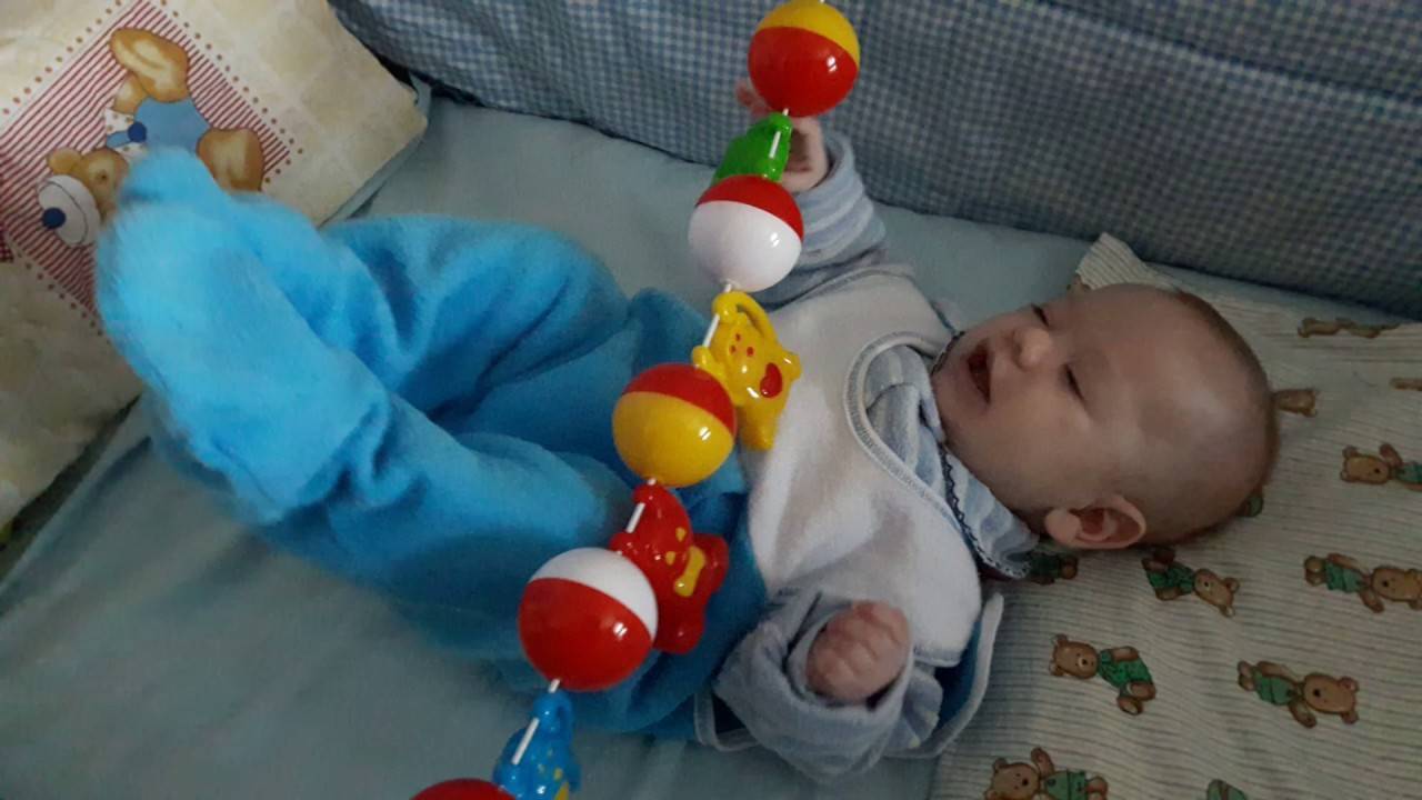 Погремушки для новорожденных на кроватку и в коляску: во сколько месяцев ребенок начинает их держать