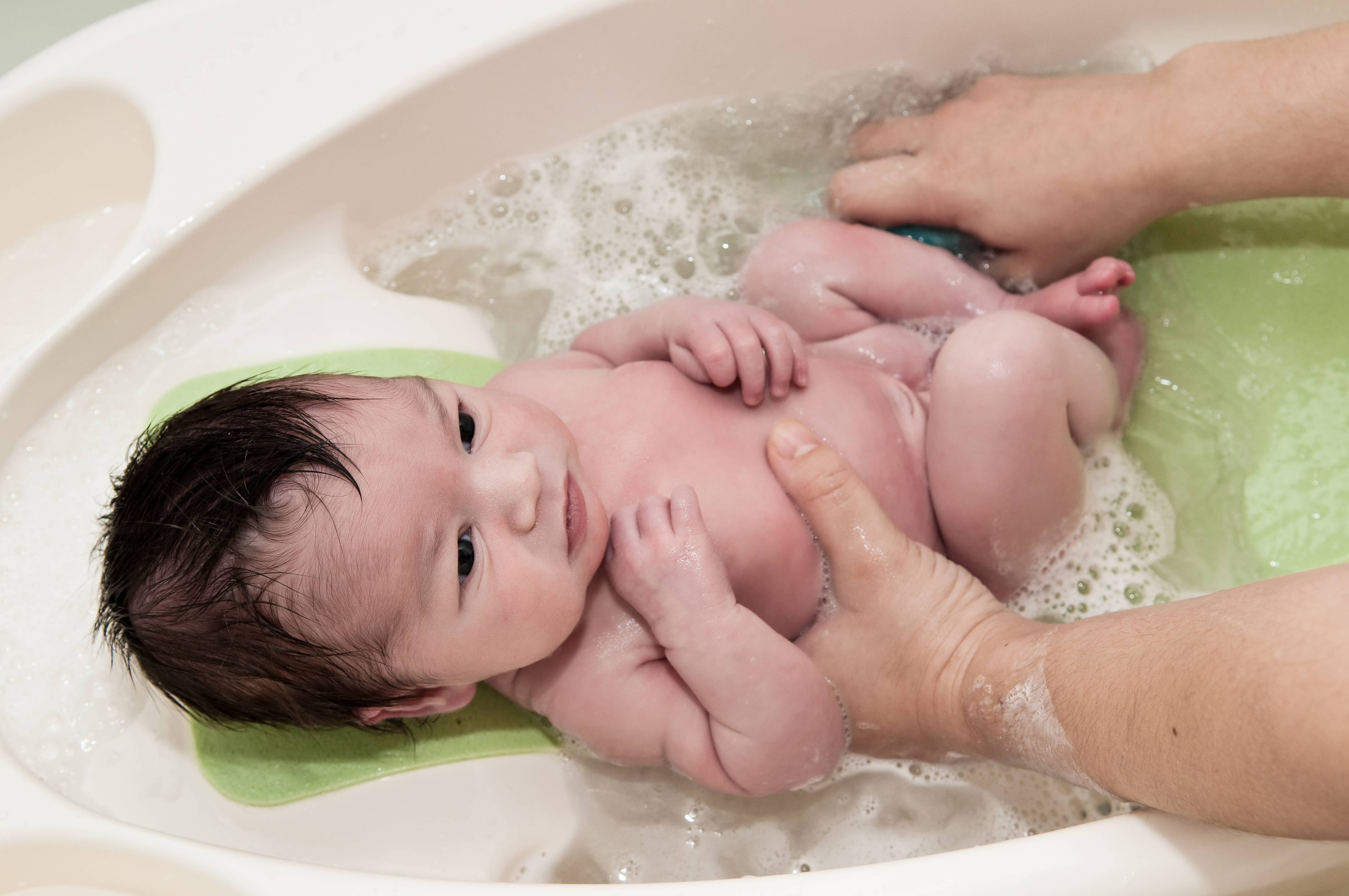 Первая гигиеническая ванна. Пуканье новорожденного. Купание новорожденного ребенка. Купание новорожденного мальчика. Ванночка для детей.